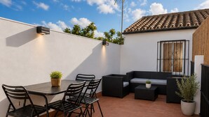 A patio with a table and chairs, a sofa, and a potted plant.