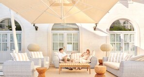 A covered outdoor seating area with wicker furniture and large lamps. - Heritage Hotel Kastelet (Tucepi)