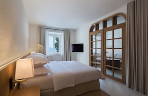 A hotel room with a bed, a TV, a window, and a view of the outdoors. - Heritage Hotel Kastelet (Tucepi)