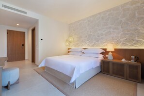 A hotel room with a bed, bedside table, lamp, and a stone wall. - Heritage Hotel Kastelet (Tucepi)