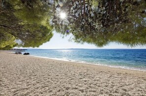 A beach with a clear view of the sea, a sandy shore, and some rocks. - Heritage Hotel Kastelet (Tucepi)