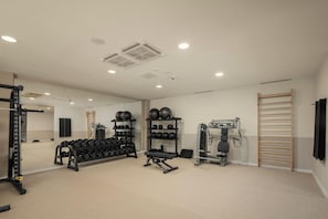 A gym with exercise equipment, a mirror, and a wooden rack. - Heritage Hotel Kastelet (Tucepi)