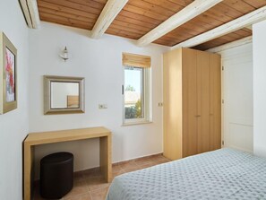 A bedroom with a bed, a wooden wardrobe, a bedside table, a mirror, and a window. - Eliathos Residence Houses Archanes (Archanes-Asterousia)