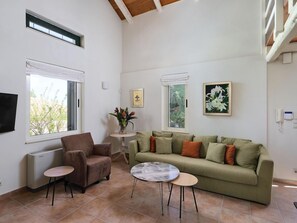 Una sala de estar con un sofá, dos sillones, una mesa de centro y un televisor.