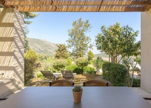 Un patio al aire libre con una mesa y sillas, una planta en maceta y vistas a un paisaje montañoso.