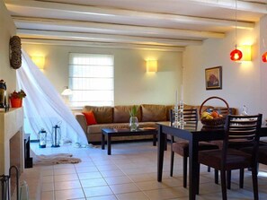 Un salon avec un canapé, une table à manger, des chaises et une fenêtre.