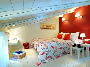 A bedroom with a bed, bedside tables, a lamp, a red wall, and a painting. - Eliathos Residence Houses Archanes (Archanes-Asterousia)