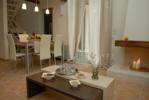 Un coin repas avec une table dressée pour quatre personnes, des chaises, une table basse et un vase contenant des fleurs séchées.