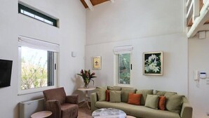 Ein Wohnzimmer mit einer Couch, zwei Sesseln, einem Couchtisch und einem Fernseher.