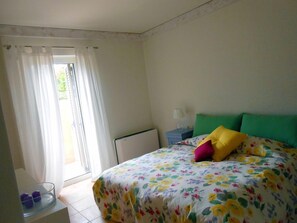 Une chambre à coucher avec un lit, une table de chevet, une lampe et une fenêtre avec des rideaux.