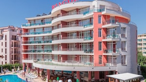 Ein mehrstöckiges Hotel mit Balkonen, einem Schwimmbad und Sitzgelegenheiten im Freien.