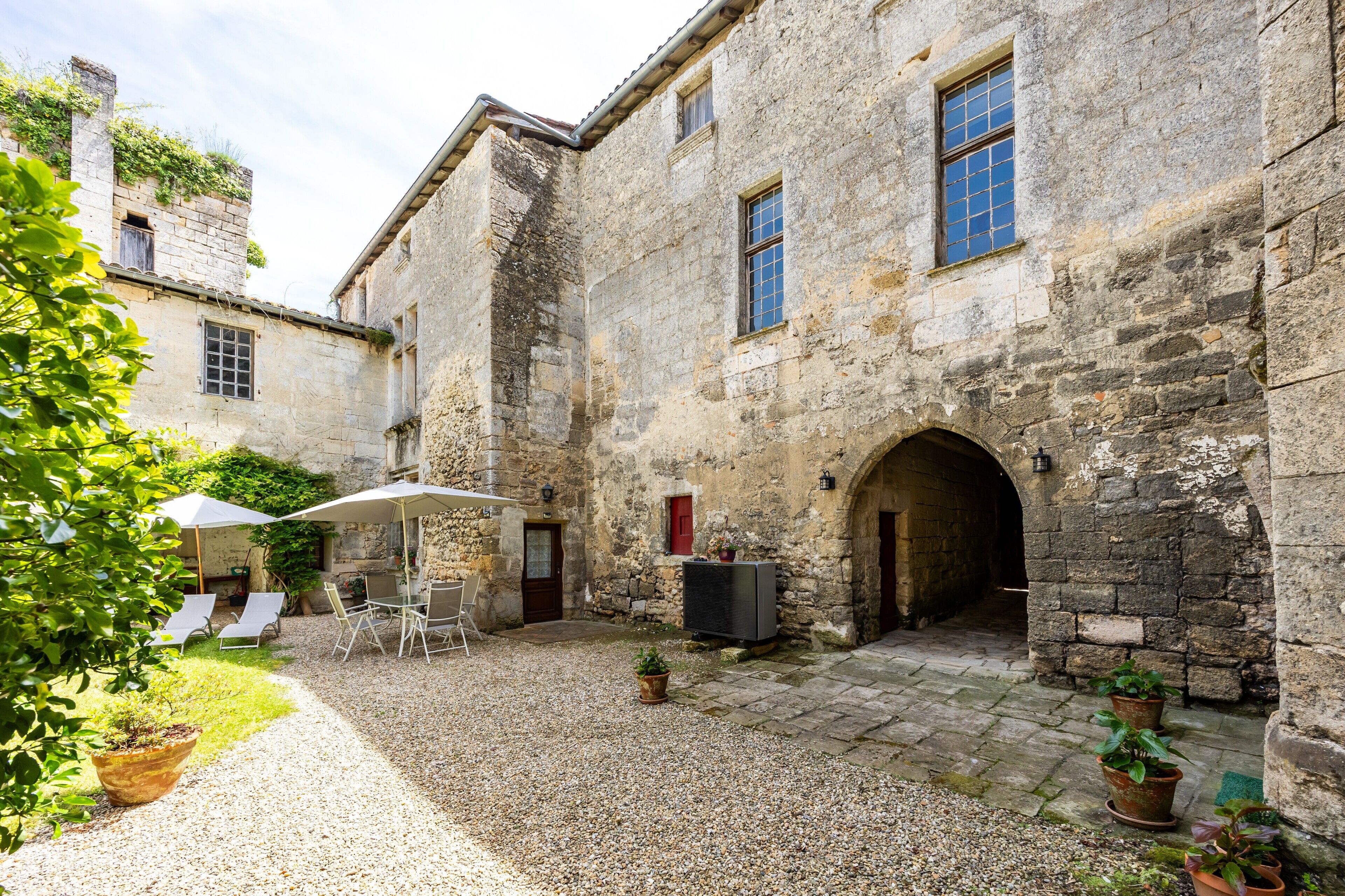 A courtyard with stone buildings, outdoor seating, and potted plants.