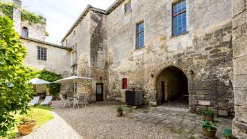A courtyard with stone buildings, outdoor seating, and potted plants.