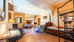 A cozy room with a sofa, a table with a lamp, a bed with a metal frame, a fireplace, and a dining area.