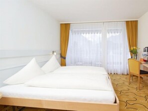 Habitación de hotel con una cama individual, un escritorio y una silla.