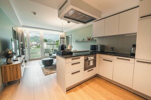 A modern kitchen with a large island, built-in appliances, and a view to the outside. - Aparthotel Goldey (Unterseen)