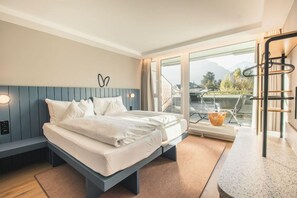 A modern bedroom with a bed, a bench, a view of the outdoors, and a balcony with a railing. - Aparthotel Goldey (Unterseen)