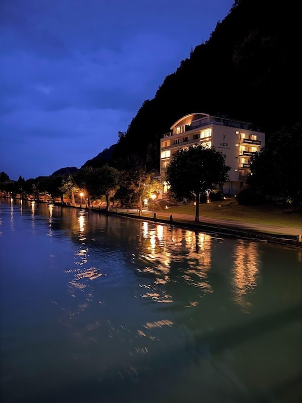 A multi-story hotel with a pool, surrounded by trees and a mountain backdrop. - Aparthotel Goldey (Unterseen)