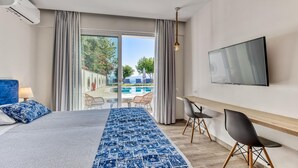 A hotel room with a bed, a TV, a desk, and a view of an outdoor swimming pool. - Sirocco Hotel (Corfu)