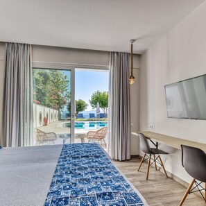 A modern hotel room with a bed, a desk, a TV, and a view of a swimming pool. - Sirocco Hotel (Corfu)
