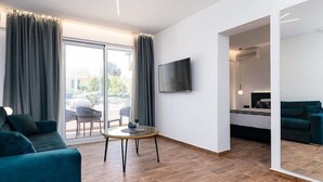 A modern hotel room with a sofa, a small round table, a TV mounted on the wall, and a balcony with curtains. - Sirocco Hotel (Corfu)
