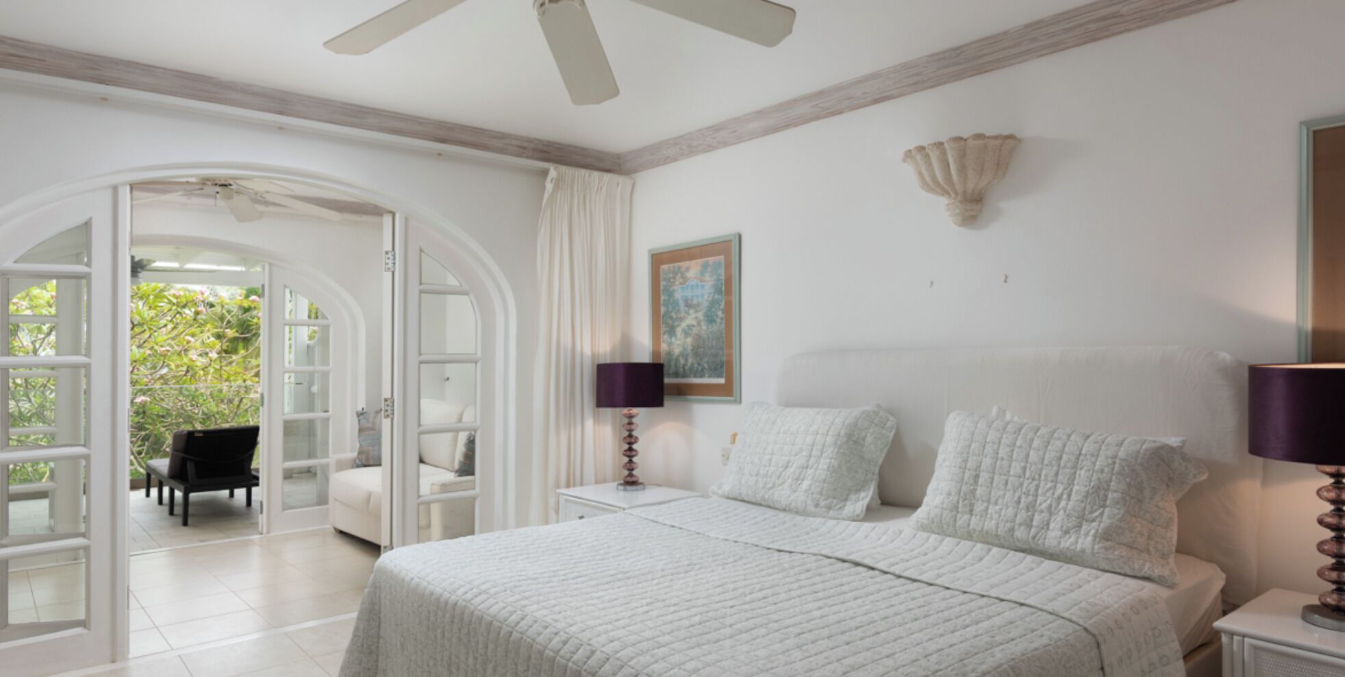 A bedroom with a bed, two bedside tables, a chair, and a door leading to a balcony.