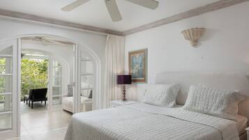 A bedroom with a bed, two bedside tables, a chair, and a door leading to a balcony.
