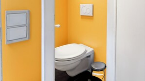 Un bagno piccolo con il water, una levetta bianca a parete e uno sgabello.