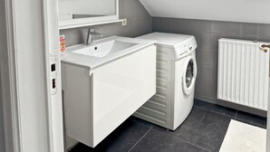 Un bagno moderno con lavabo integrato, lavatrice e termosifone.