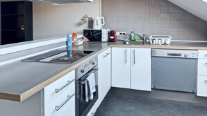 Una cucina moderna con forno integrato, microonde, lavastoviglie Bosch e cappa aspirante in acciaio inossidabile.