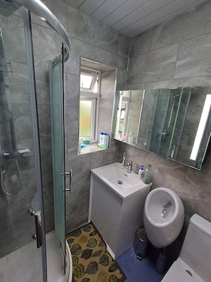A bathroom with a glass shower enclosure, a white sink, a toilet, and a mirror above the sink. - Room-single Room in CV6 4DF Near CBS Are (Coventry)