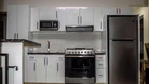 A kitchen with white cabinets, a microwave, a stove, and a refrigerator. - Beautiful and Cozy With sea Views (Las Terrenas)
