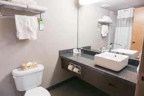 A hotel bathroom with a toilet, two sinks, a mirror, and a towel rack. - Days Inn Calgary Airport (Calgary)