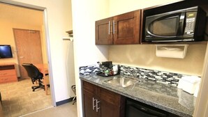 A compact kitchen with a microwave, sink, and a small countertop area. - Days Inn Calgary Airport (Calgary)