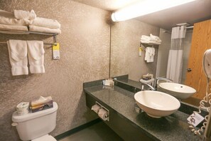 A bathroom with a toilet, two sinks, a mirror, towels on a rack, and a hairdryer.
