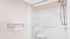 Un baño moderno con cabina de ducha de vidrio, un perchero blanco y un taburete.
