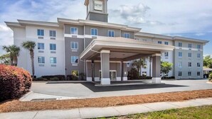 A multi-story hotel with a covered entrance, a prominent sign, and a parking lot. - Sleep Inn & Suites Panama City Beach East (Panama City Beach)