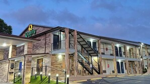Un hotel de varios pisos con fachada de piedra, un llamativo letrero de 'Quality Inn' y una escalera que conecta los niveles.