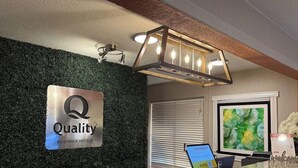 Una recepción de hotel con un cartel de 'Quality by Choice Hotels', una pantalla digital y un moderno aplique.
