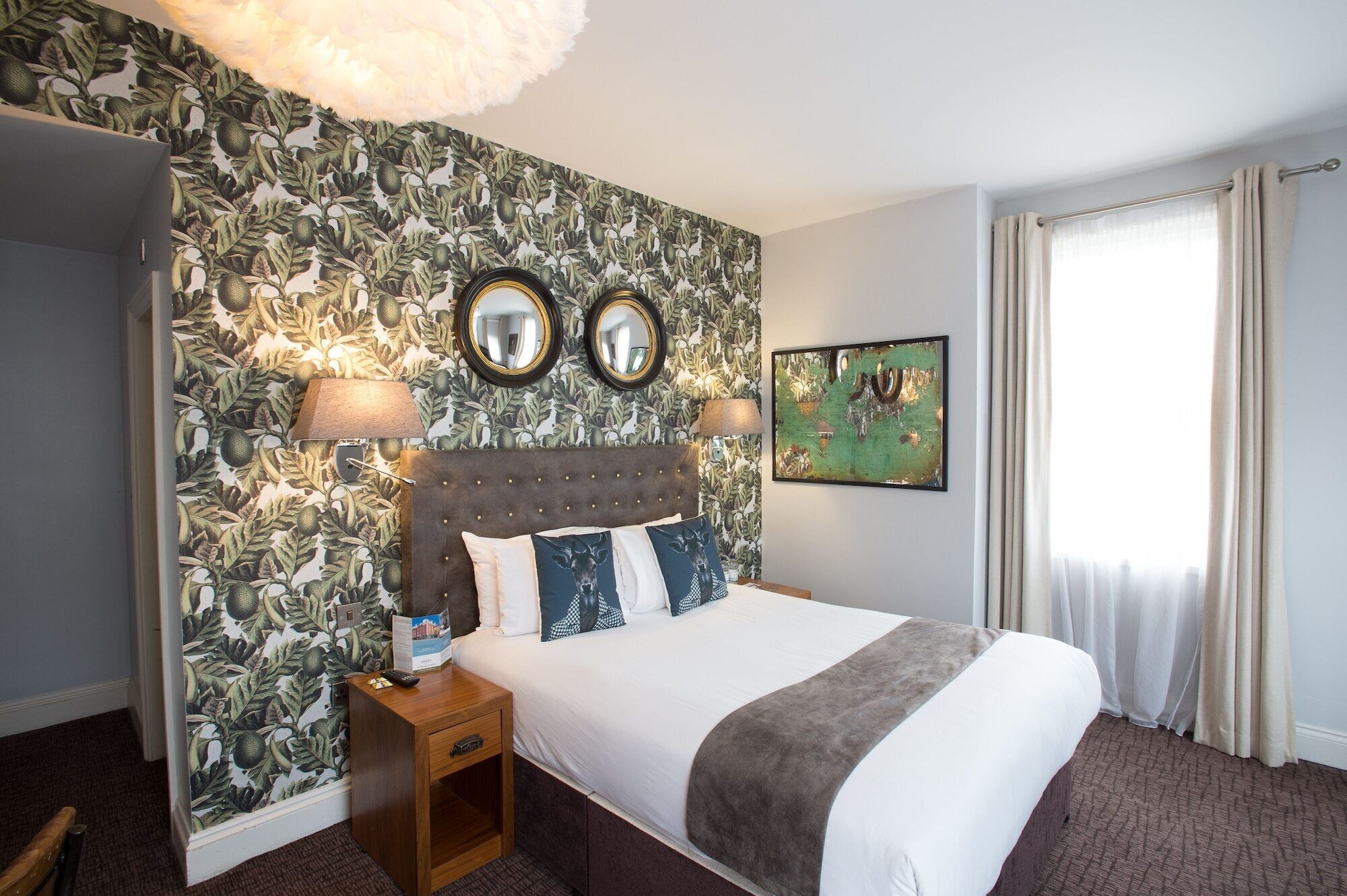A hotel room with a large bed, two wall mirrors, a nightstand, a lamp, and a painting.