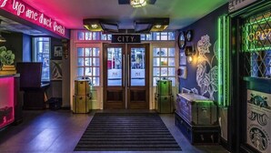A hotel entrance with a neon sign, a reception desk, and a staircase leading to the lobby. - Nottingham City Centre Hotel by Sunday (Nottingham)