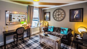 A room with a plaid floor, a sofa with a leopard print throw, a vintage trunk, a desk with a lamp, and a large wall clock. - Nottingham City Centre Hotel by Sunday (Nottingham)
