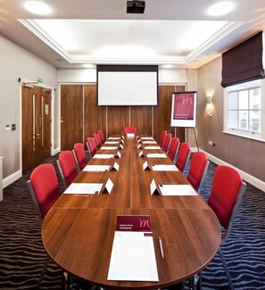 A conference room with a long table, red chairs, a projector screen, and a presentation board. - Mercure Nottingham City Centre Hotel (Nottingham)