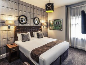 A hotel room with a large bed, two bedside lamps, a headboard with a mirror, a painting on the wall, and a window with curtains. - Nottingham City Centre Hotel by Sunday (Nottingham)