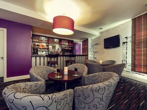 A bar area with seating, a television, and a patterned carpet. - Mercure Nottingham City Centre Hotel (Nottingham)