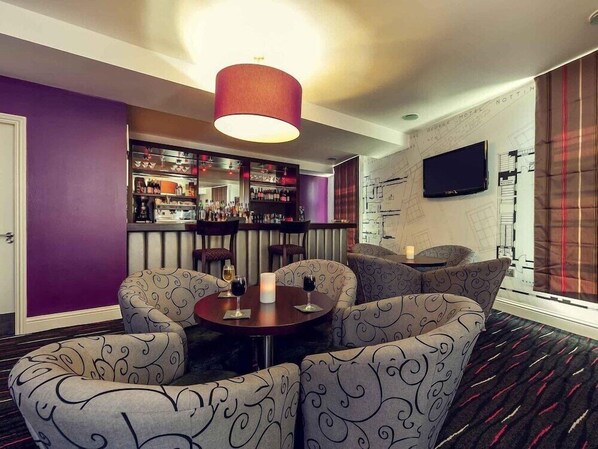 Eine Bar mit Sitzgelegenheiten, einem Fernseher und einem gemusterten Teppich.