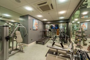 Un gimnasio con equipo de ejercicio, una cinta de correr y una pantalla de televisión.