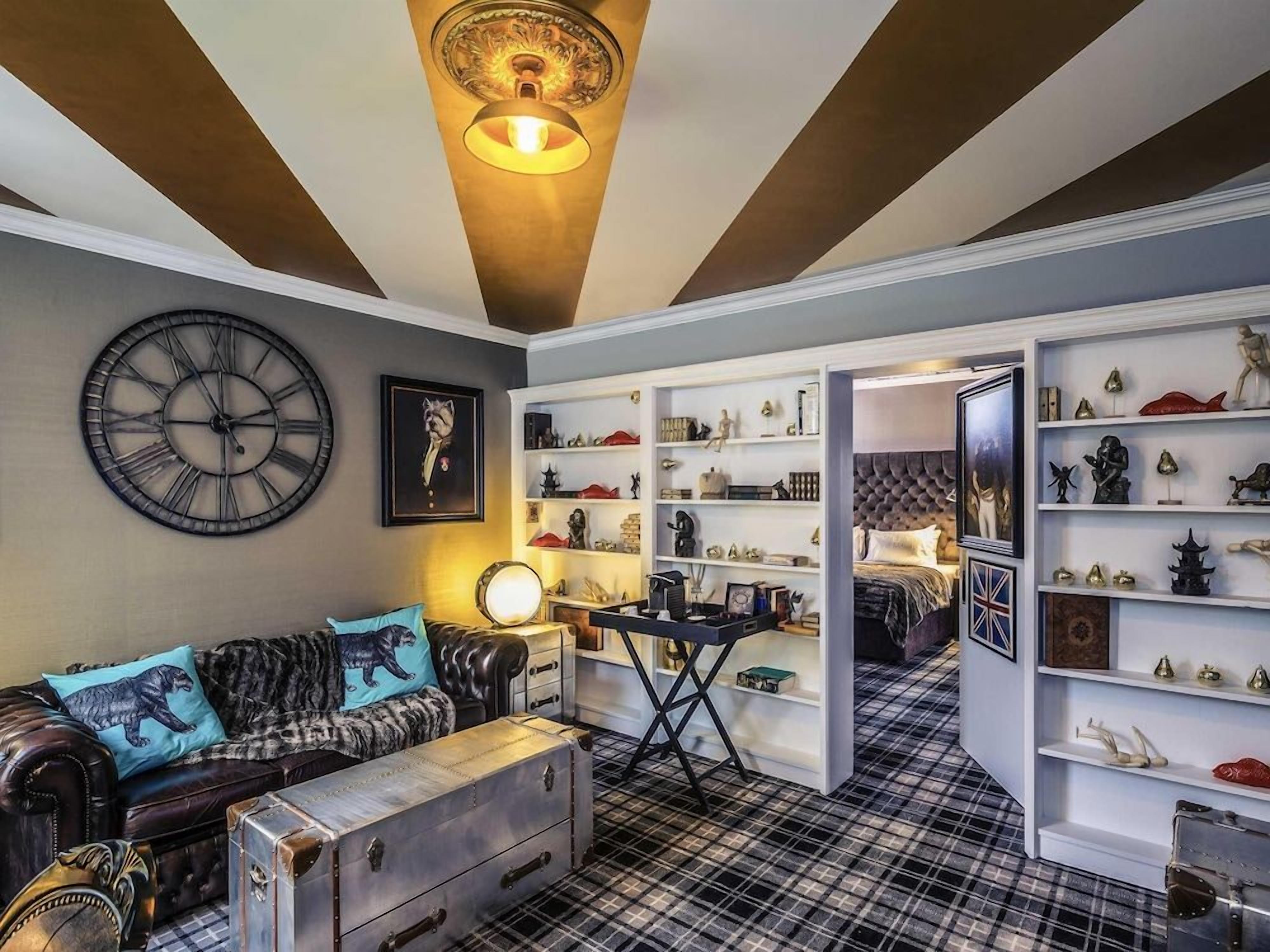 Una habitación con un reloj grande, un sofá con cojines de estampado de leopardo, un escritorio y estanterías con varios objetos decorativos.
