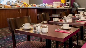 A hotel dining area with tables set for breakfast, including cups, saucers, and utensils. - Nottingham City Centre Hotel by Sunday (Nottingham)