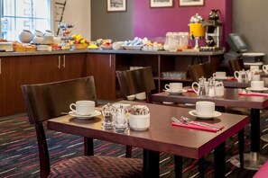 Ein Hotel-Speisesaal mit gedeckten Tischen für das Frühstück, einschließlich Tassen, Untertassen und Besteck.
